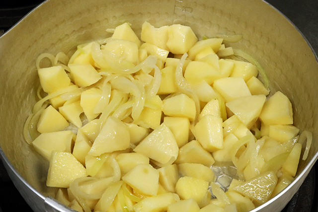 2. 鍋にバター半量を溶かし、玉ねぎを中火で炒め、香りが出てきたら残りのバター・じゃがいも・りんごを加えてサッと炒める。