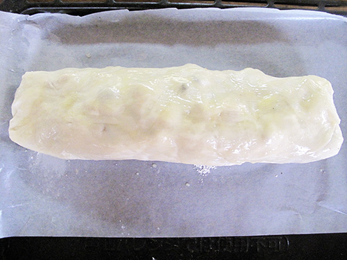 7. 仕上げ<br>巻き終わりを下にしてクッキングシートにのせて溶かしバターを塗る。200℃に熱しておいたオーブンに入れ、途中1～2回表面に溶かしバターを塗りながら45分焼いて完成！