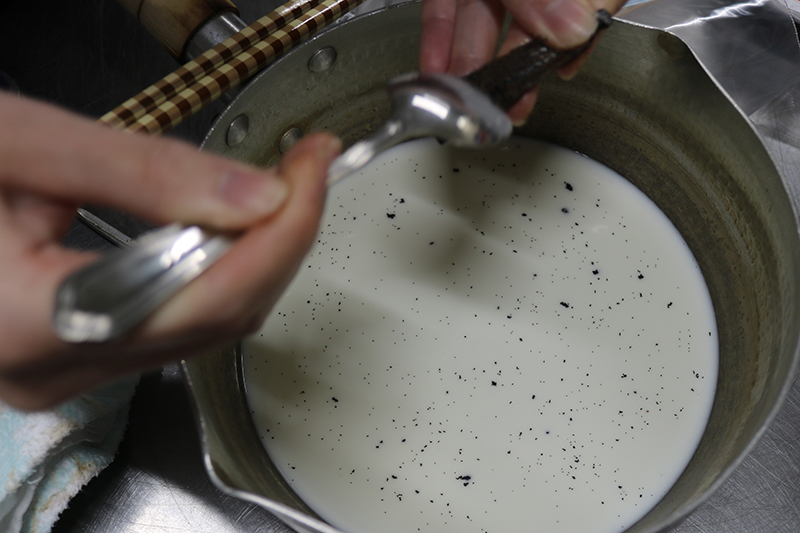 9. カスタードクリーム<br>鍋に牛乳を入れ、縦二つに切ったバニラビーンズの中の種をスプーンやナイフの背などで取り、加える。種を取ったさやも牛乳へ加え、温めて十分に香りをつける。
