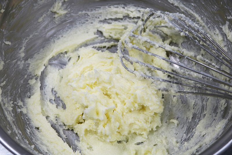2. 室温に戻したバターをボウルに入れ、泡立て器でクリーム状にする。残りのグラニュー糖（80g）を加えて、白っぽくふわふわの状態になるまですり混ぜ、卵白も1個分加えてよく混ぜる。
