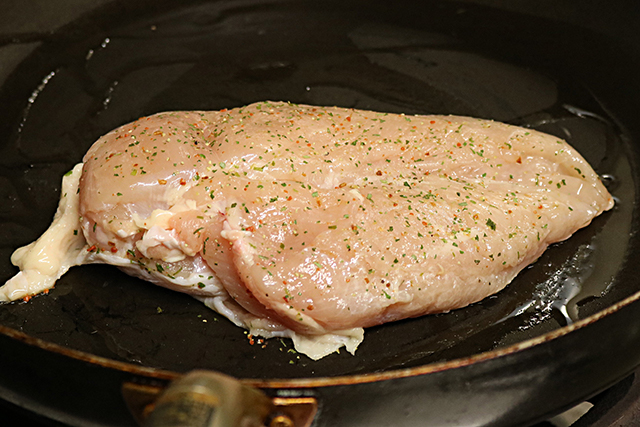 3. 熱したフライパンにオリーブオイルを入れ、鶏むね肉を皮目から焼く。<br>（肉が厚いので切れ目を入れたり、蓋をしてじっくり火を通す）