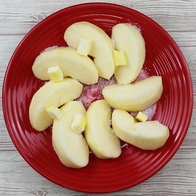 2. りんごを深めの皿に並べ、グラニュー糖を振りかけ、角切りバターを散らす。