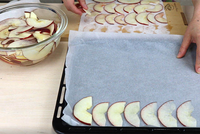 りんごの水分をペーパータオルなどで拭き取り、クッキングペーパーを敷いた天板に並べ、100℃で予熱したオーブンで乾燥させる。
