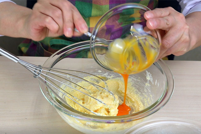 卵黄を2回に分けて加え、その都度よく混ぜなめらかな状態にする。<br>（※卵黄を一度に加えると分離するため、2回に分けて加える）