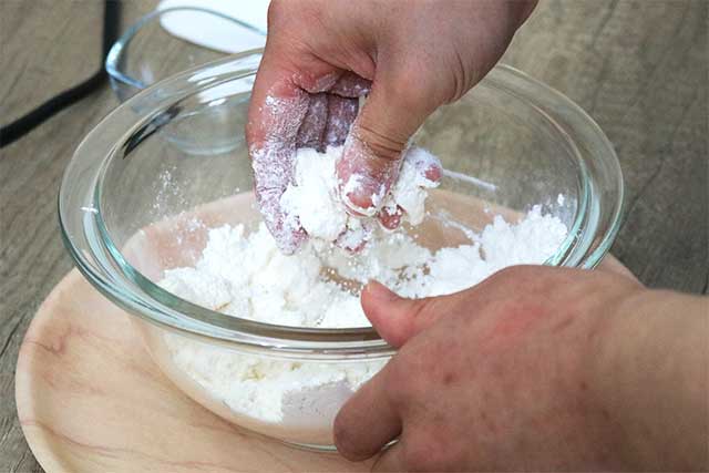4.冷蔵庫から出した冷えたままのバターをサイコロ状に切り、ボールに入れる。 薄力粉と砂糖もその中に入れる。<br>バターを潰しながら細かくし、薄力粉と砂糖をまぶしていく。