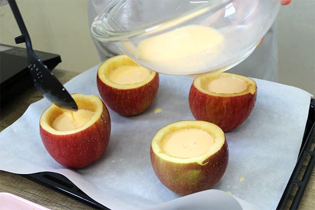 5.りんごの器に２のプリン液を流し入れ、クッキングシートを敷いた天板の上にのせ、170℃に予熱したオーブンで約40分焼く。