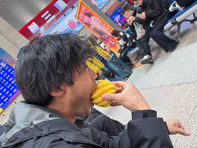 長春駅のターミナルでパイナップルをムシャムシャ食べる日本人（私） 画像